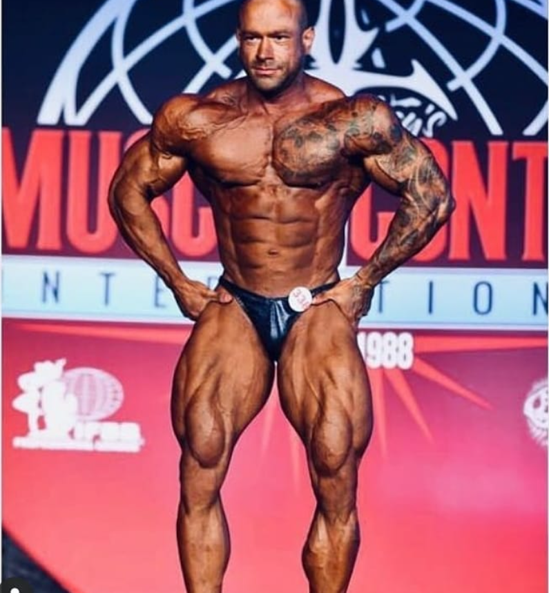 Joel Coutinho em competição, em pose frontal com as mãos na cintura